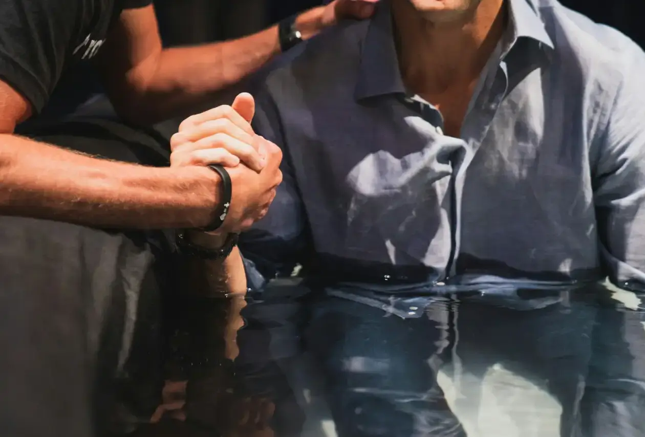 man in blue shirt getting baptised
